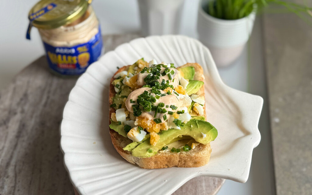 En tallrik med rostmacka med Kalles sill, ägg, avokado och gräslök.